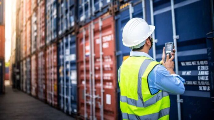 obrero trabajador-revisa-codigo-de-contenedores-en-terminal-portuaria-1-696x392